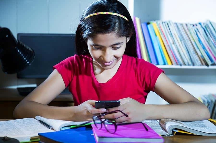 Imagem dos melhores aplicativos de planejamento de estudos para todos os alunos para iOS e Android | depositphotos_200759936-stock-photo-hand-playing-mobile-phone-book-min-min-DzTechs