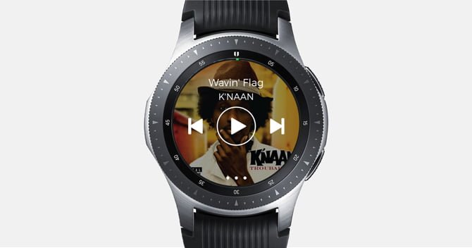 Galaxy Watch 的螢幕截圖,其中包含 Spotify 應用,背景顯示音樂控制和專輯封面。