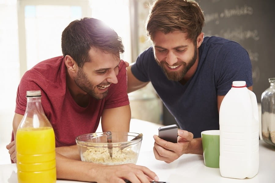 Bild der besten Mitbewohner-Apps zur Verwaltung des gemeinsamen Lebens auf iOS und Android | Two_Male_Friends_Having_Breakfast_And_Reading_Text_Message-9xvq1bgs-DzTechs