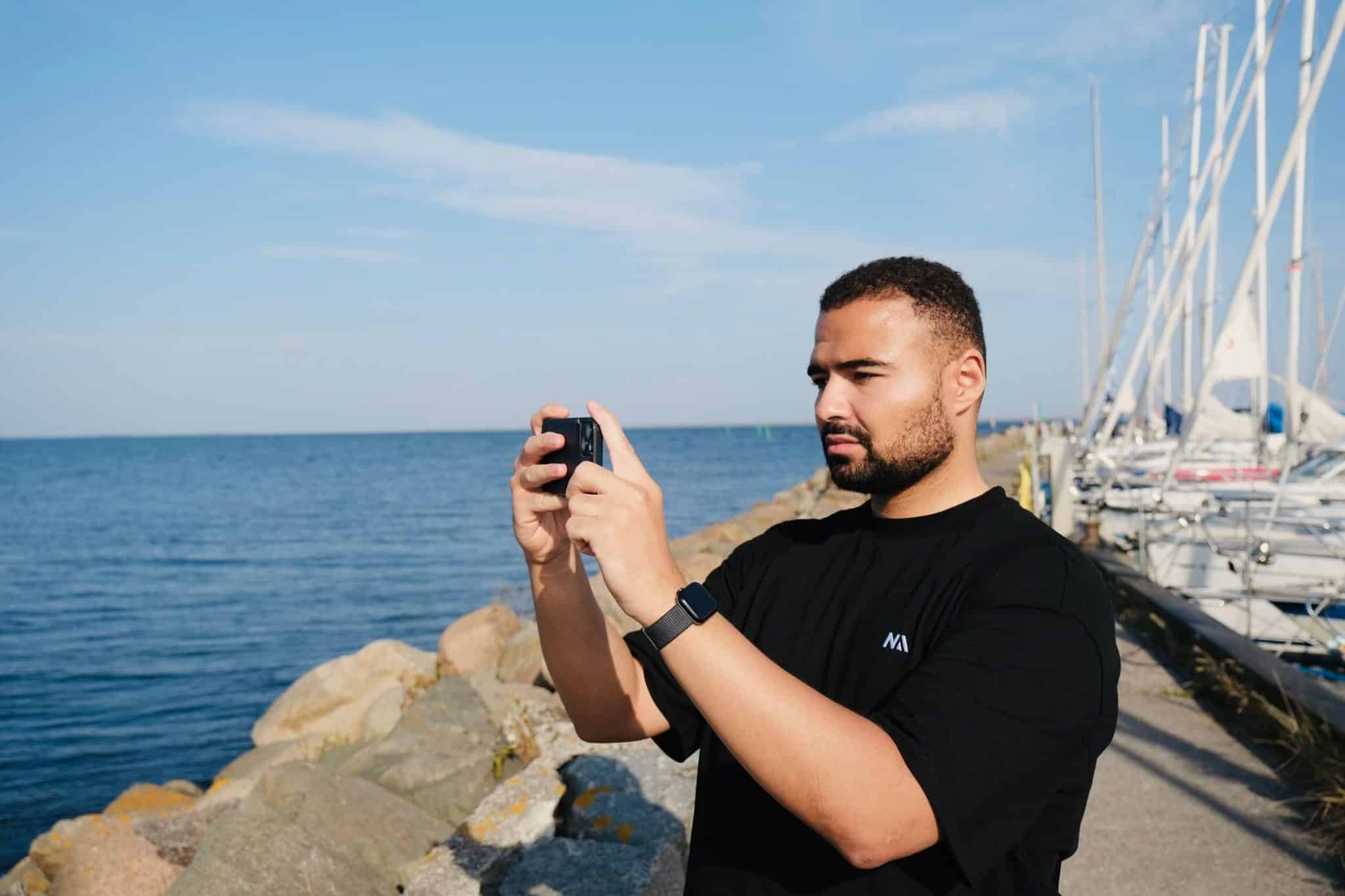 Una persona scatta una foto con il suo smartphone vicino all'oceano e alle rocce