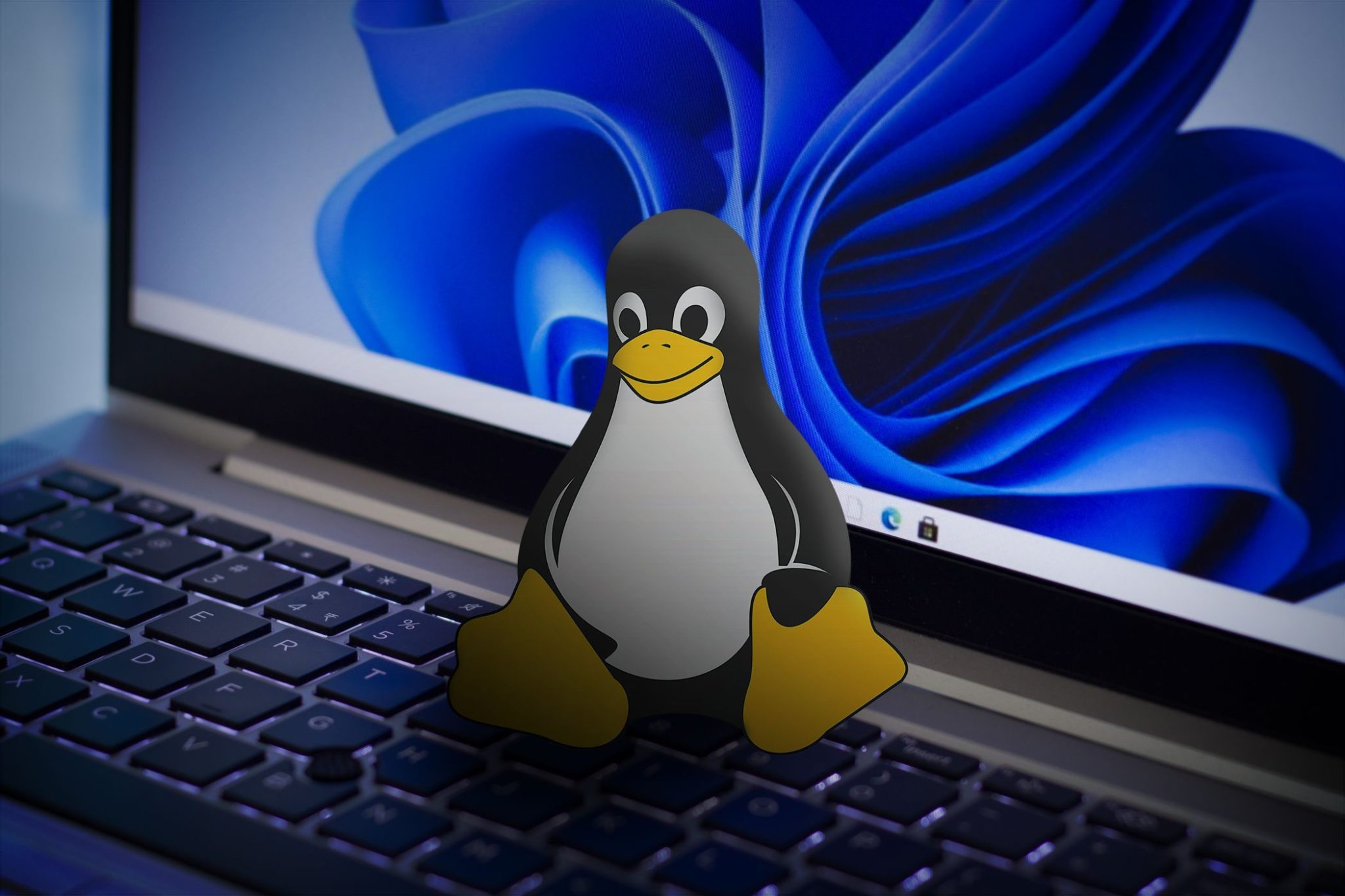 Ikona systemu Linux na klawiaturze laptopa z tapetą systemu Windows 11 na ekranie.
