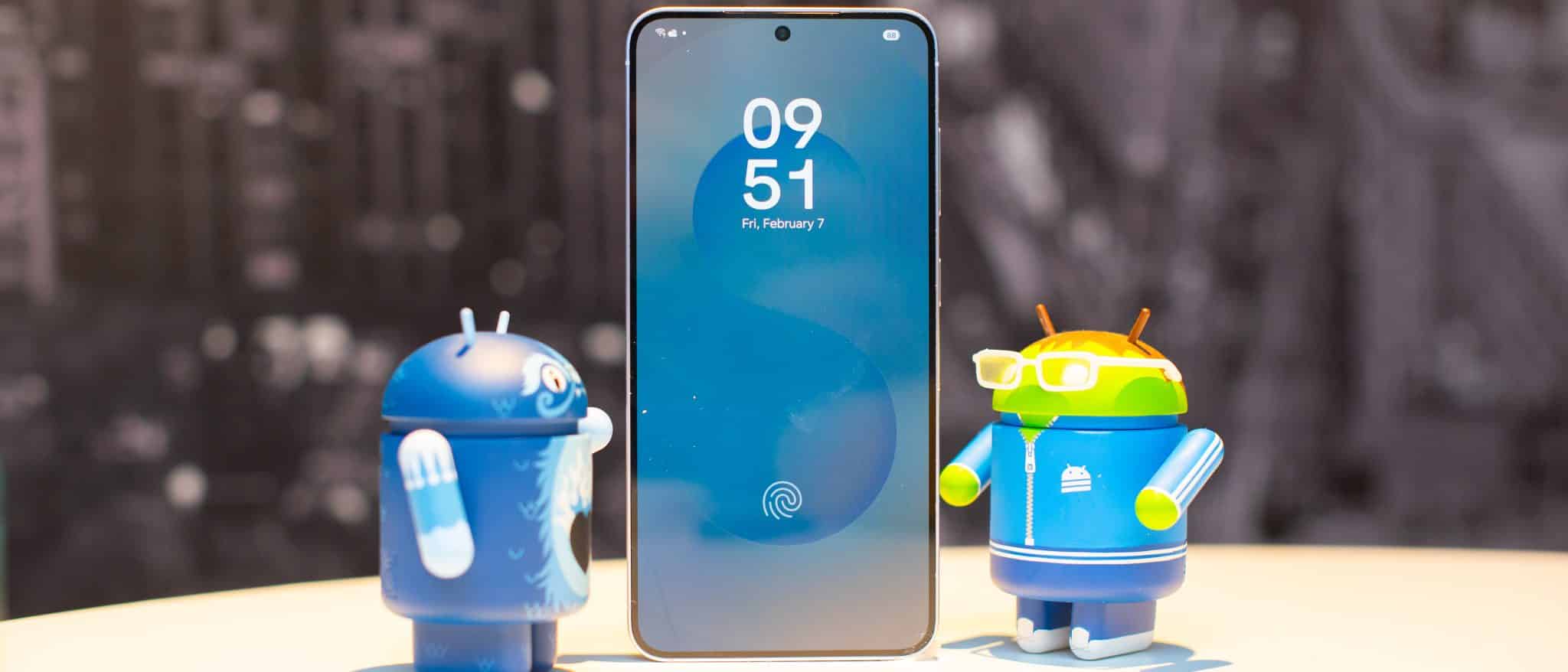 三星 Galaxy S25 手機展示鎖定螢幕,兩側各有兩個可收藏的 Android 角色,看起來很感興趣
