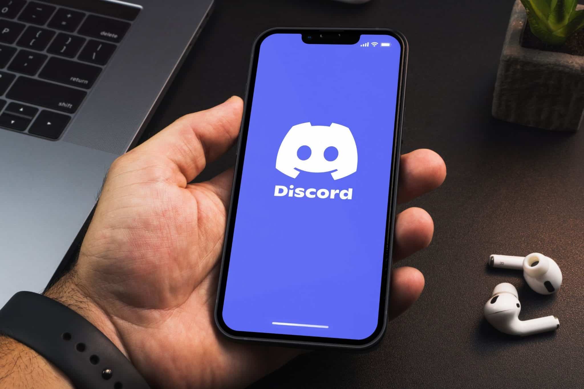 Persona che tiene in mano uno smartphone con l'app Discord