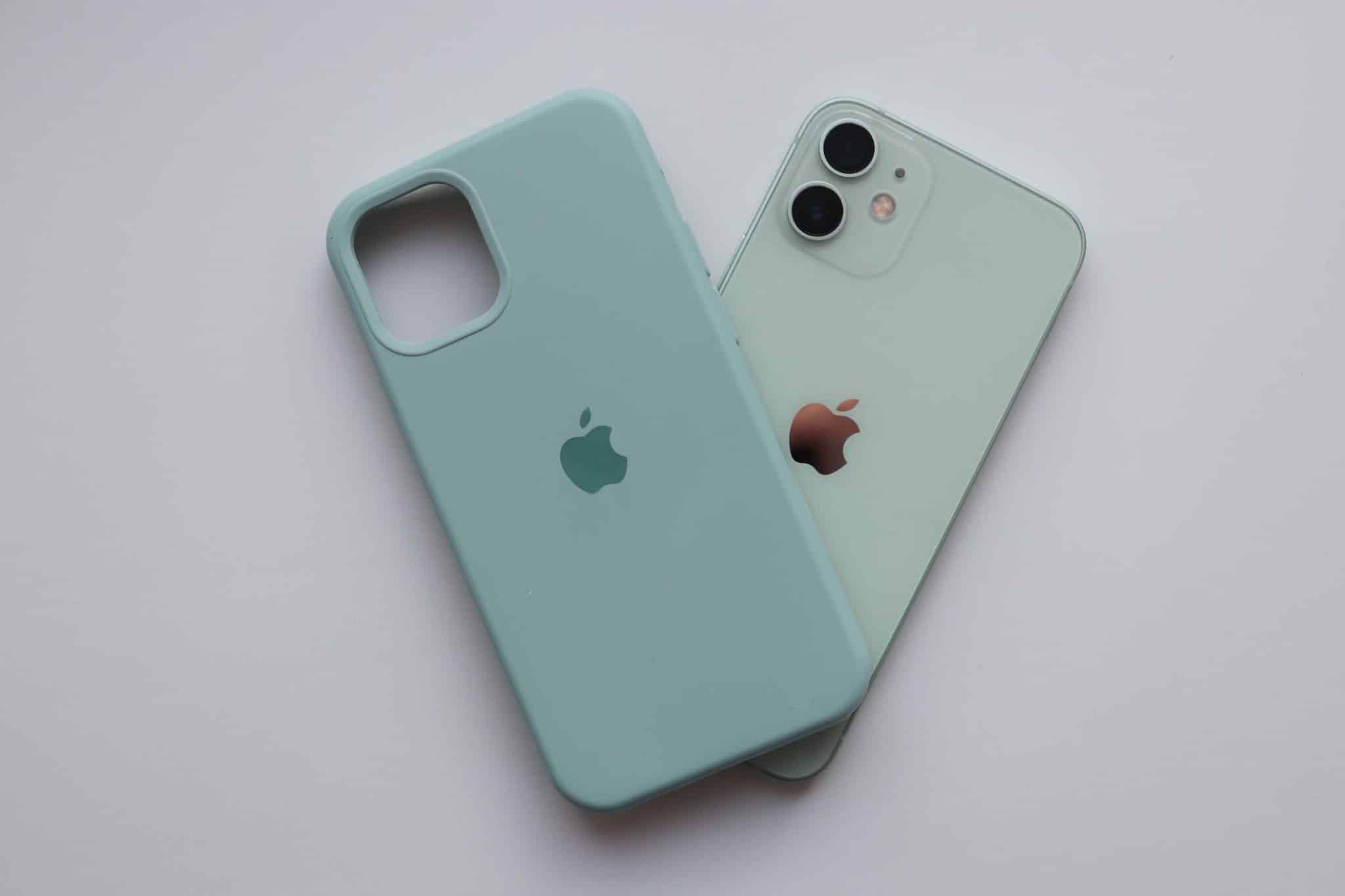 iPhone 12 w pastelowej zieleni obok silikonowego etui Apple