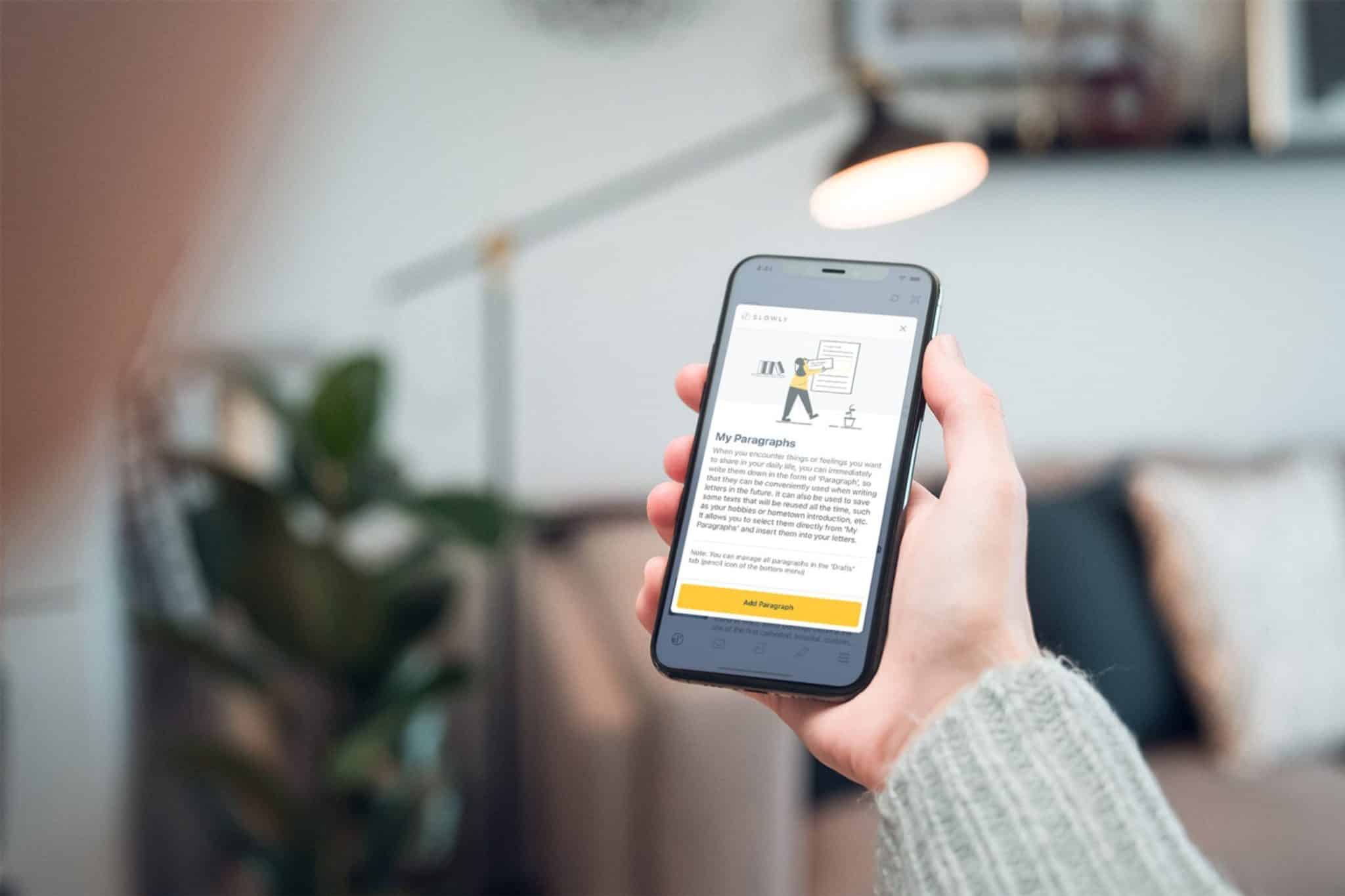 personne tenant un téléphone utilisant l'application Slowly