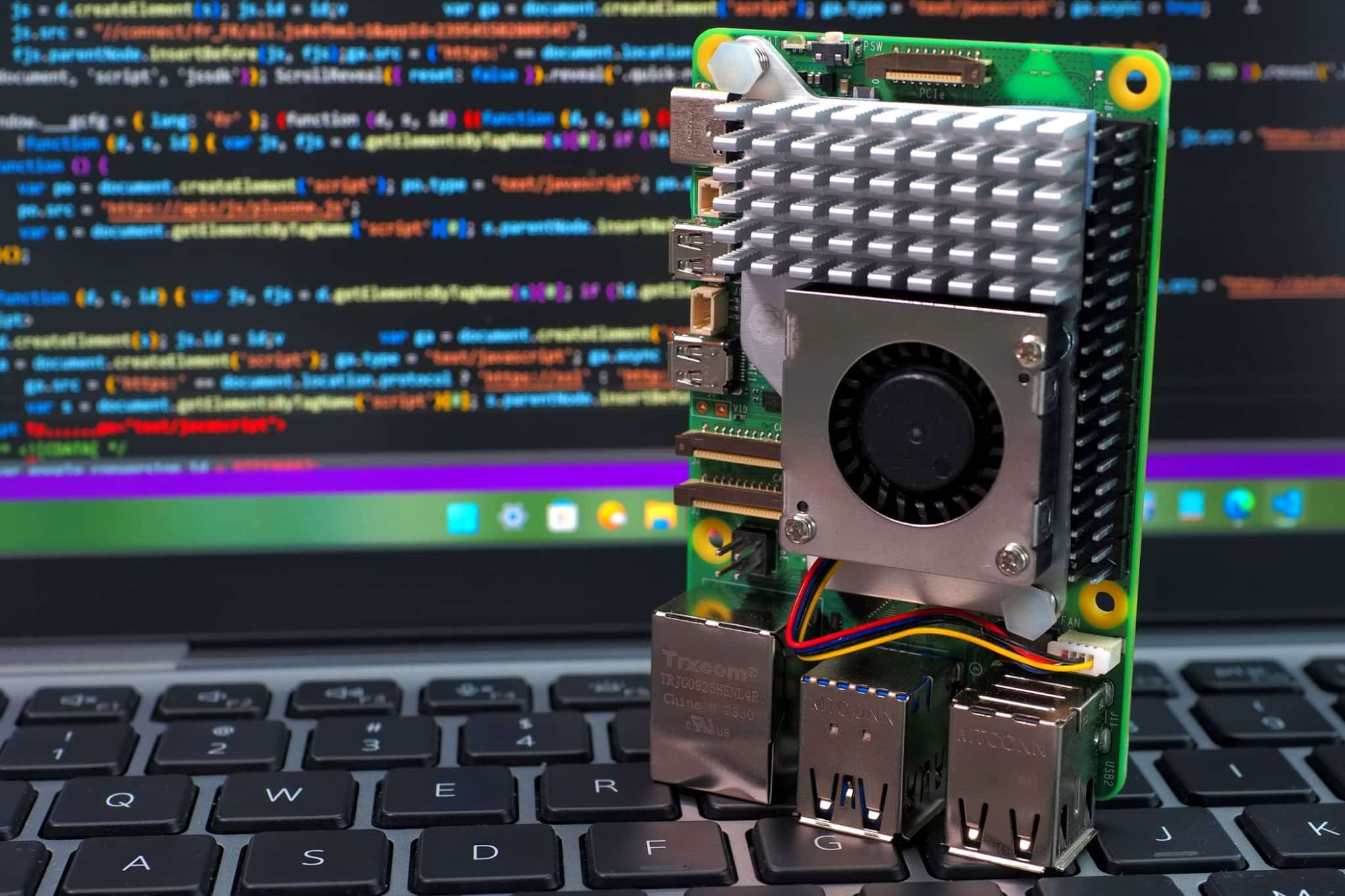 Raspberry Pi 5 steht auf Laptop-Tastatur mit Code auf Bildschirmhintergrund