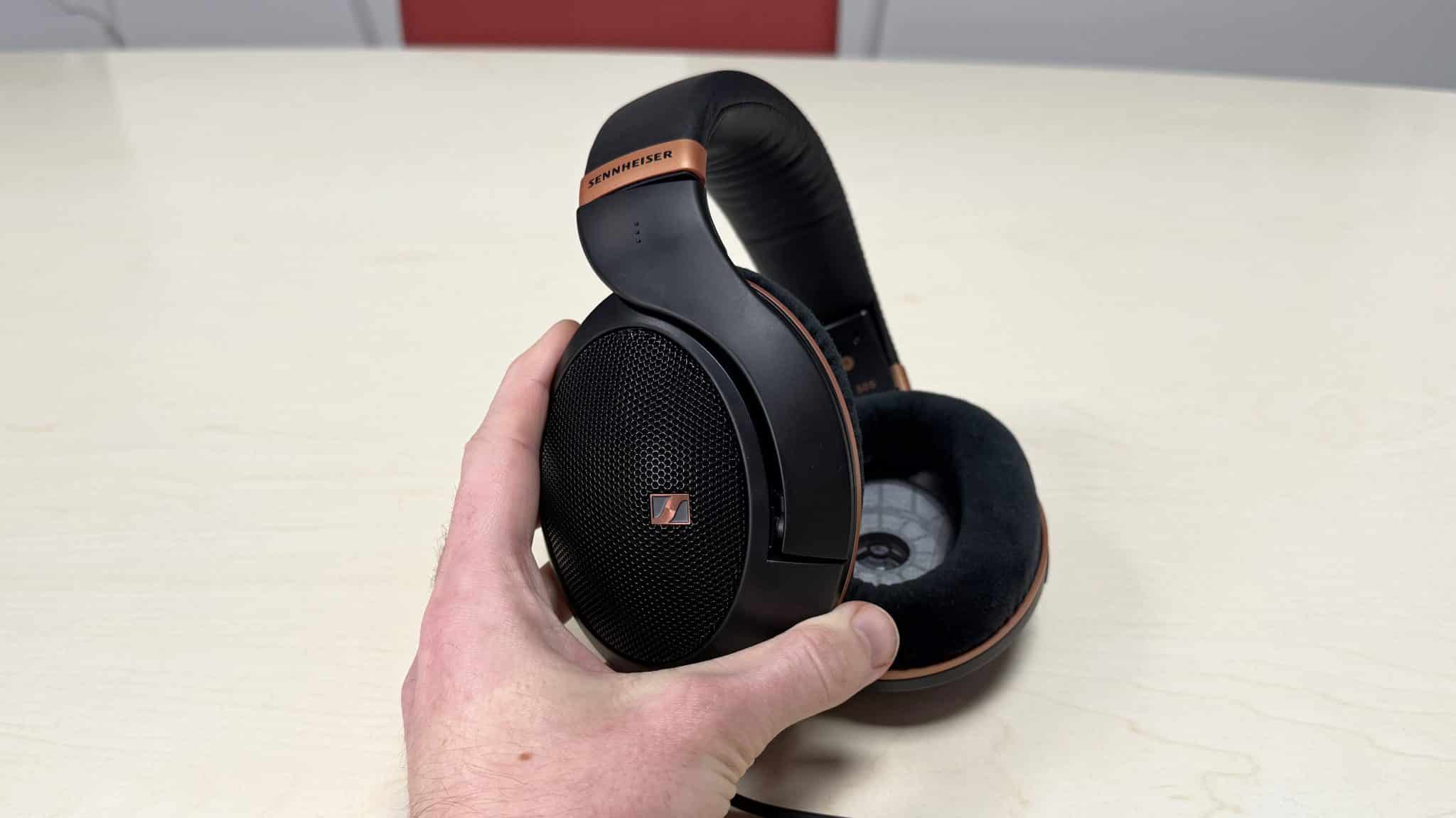 一位男士手持 Sennheiser HD 505 耳機,露出耳罩網