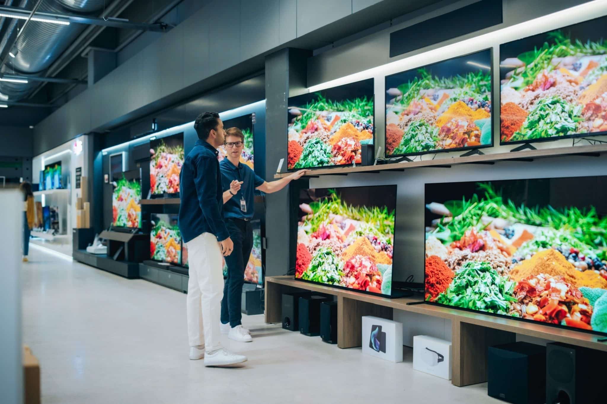 Un employé de magasin montre des téléviseurs à un client.