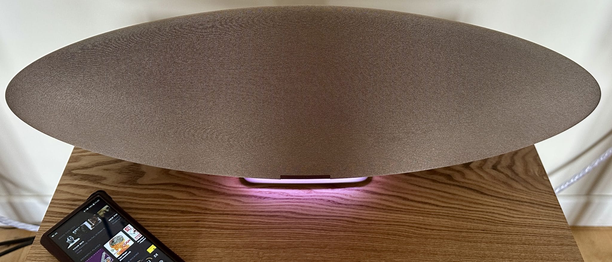 Bowers & Wilkins Zeppelin Pro Edition en un estante con luz rosa y reproductor de música al lado.