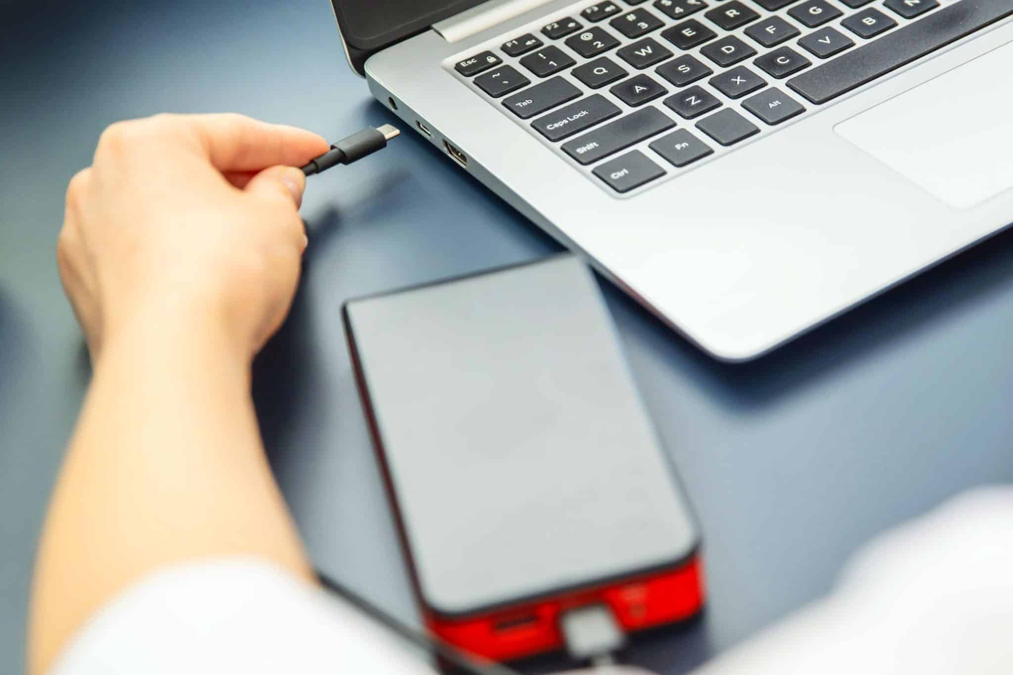 donna che collega il cavo usb c al laptop con power bank
