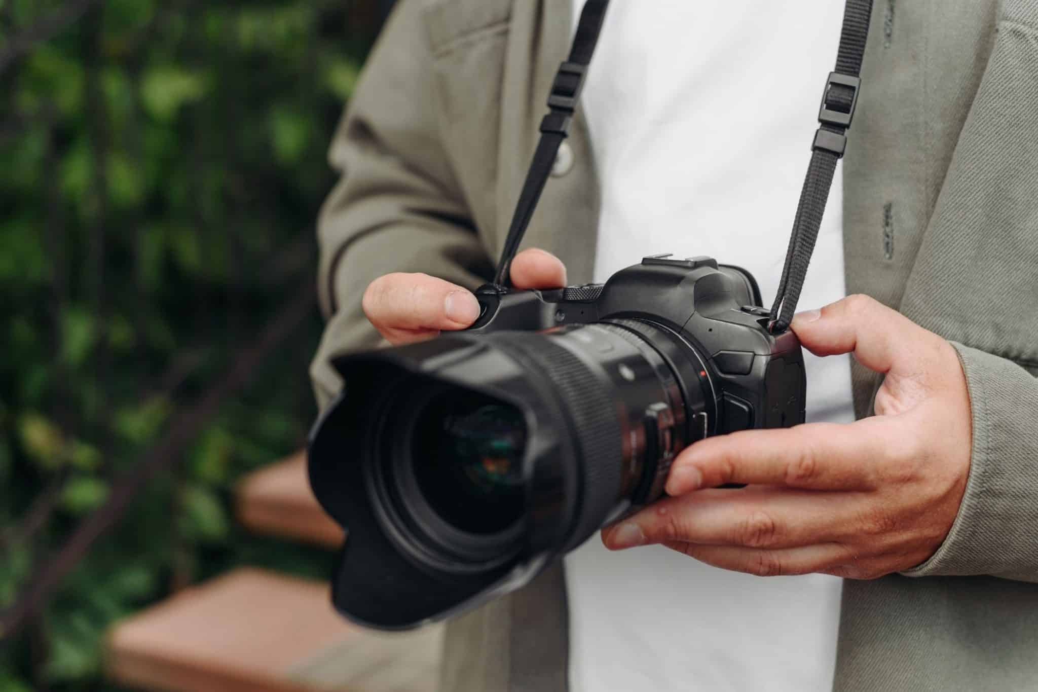 Jonge volwassen fotograaf in wit t-shirt met dslr-camera in handen