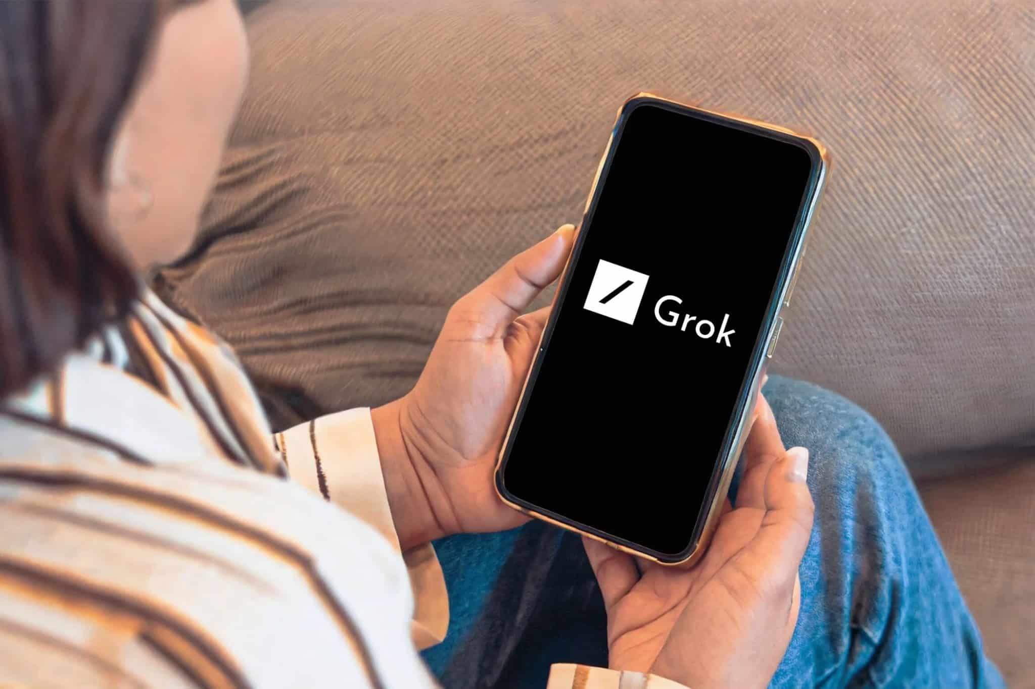 Üzerinde Grok AI logosu bulunan akıllı telefona bakan bir kişi.