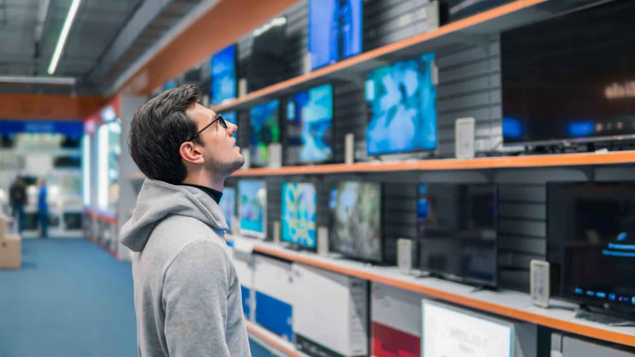 Un uomo guarda gli scaffali delle smart TV in un negozio.