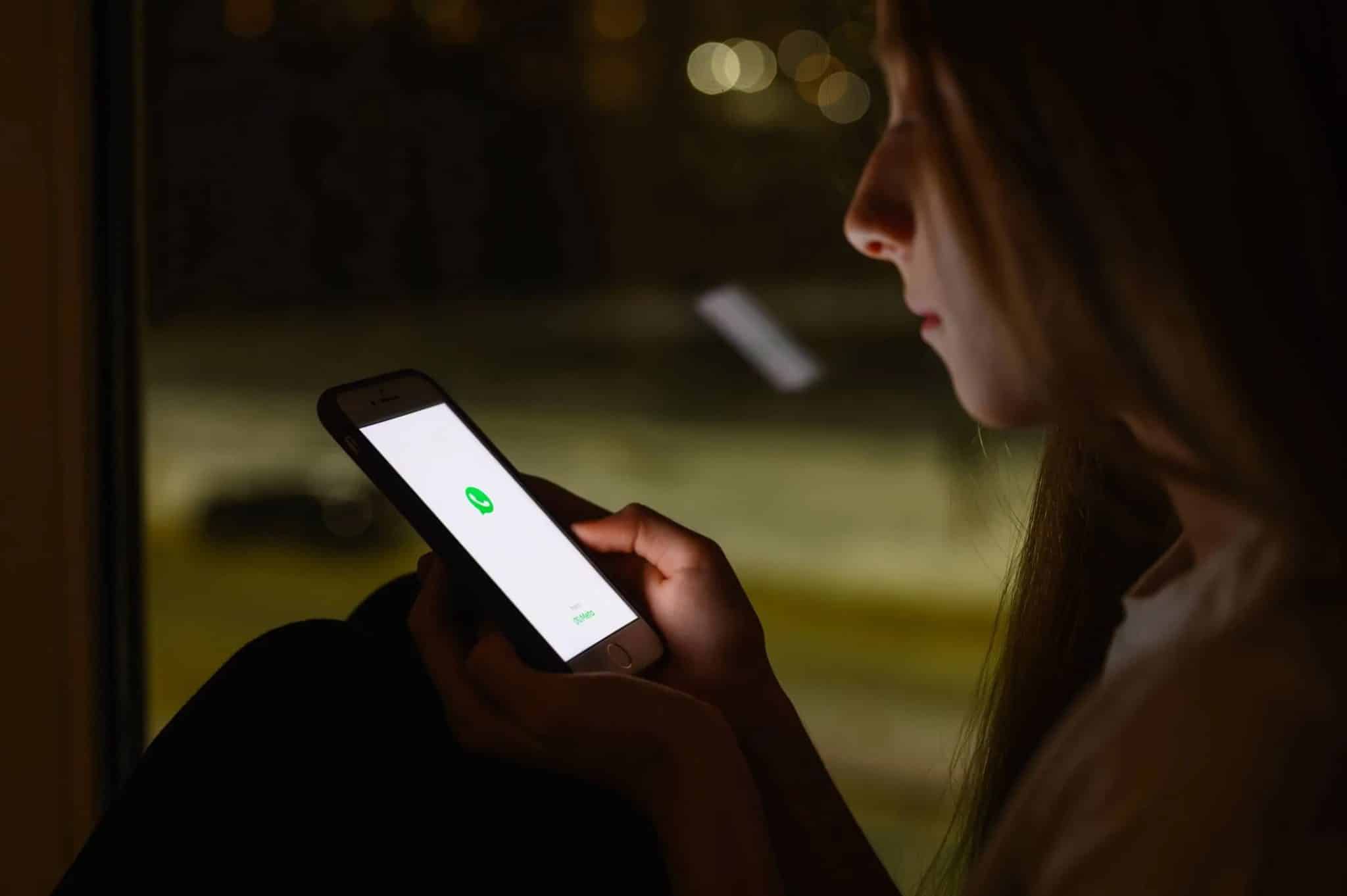 一位女士在夜間使用 iPhone,螢幕上顯示明亮的影像