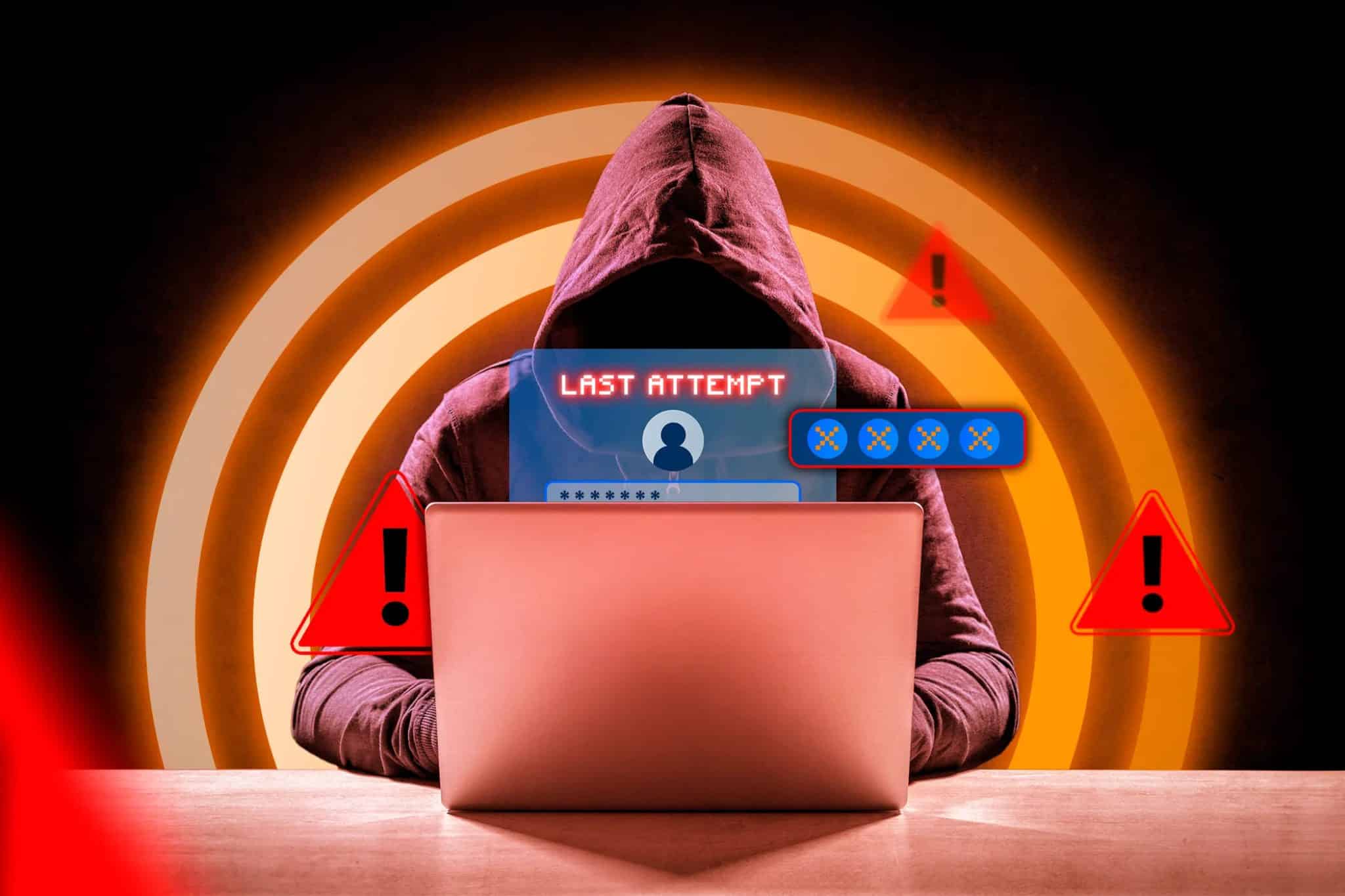 Un hacker davanti a un computer portatile con una finestra di login e alcuni segnali di avvertimento attorno ad essa.