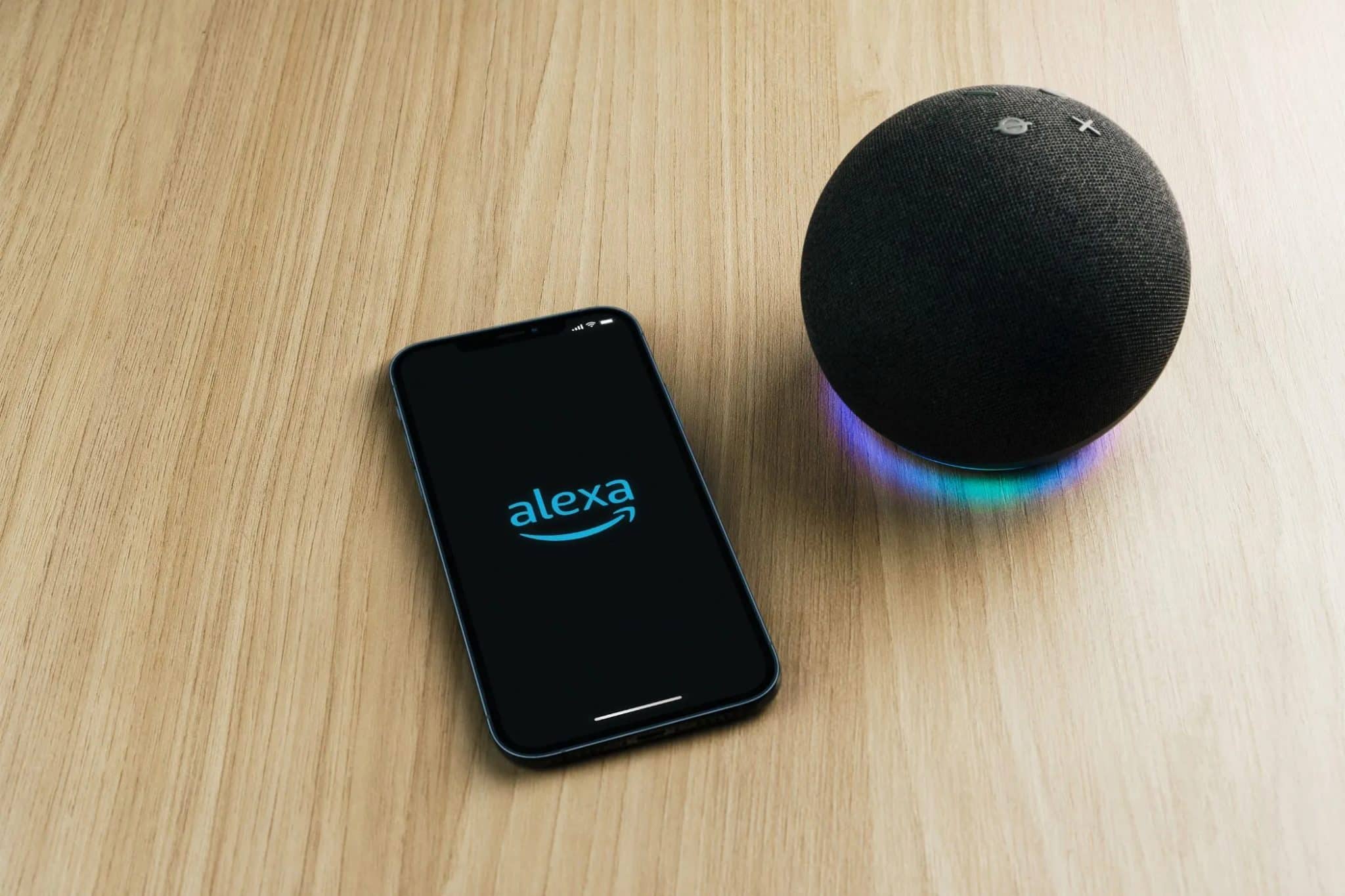 Εφαρμογή Alexa σε smartphone σε τραπέζι δίπλα σε ηχείο Echo