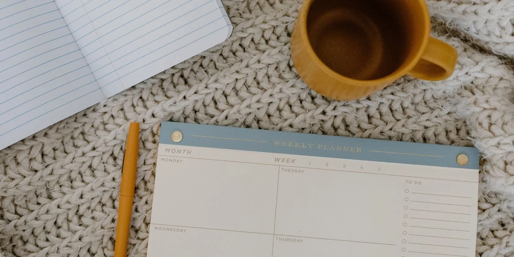 Wochenplaner, Notizbuch und Kaffee auf einem Tisch