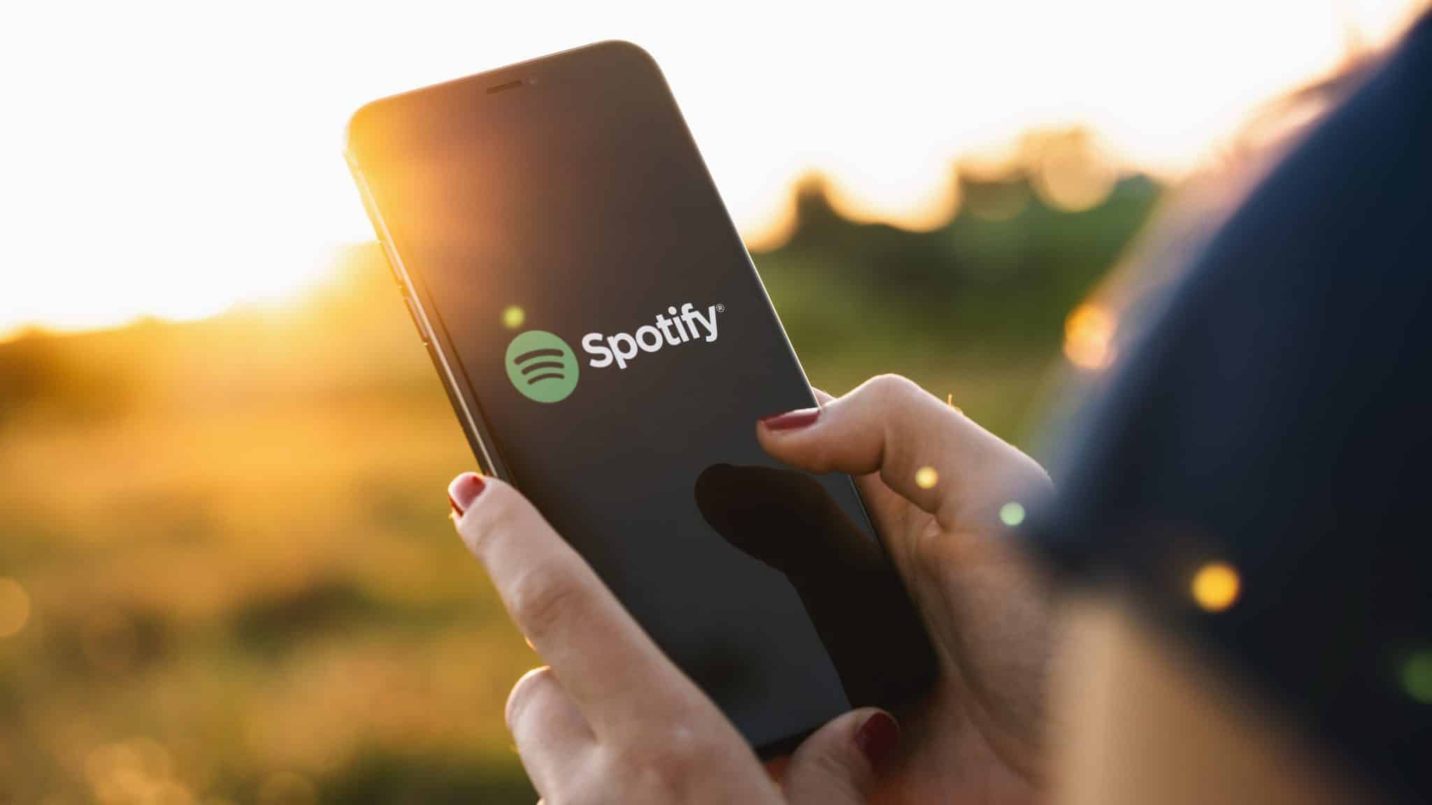 Kobieta trzymająca telefon na polu z aplikacją Spotify na ekranie