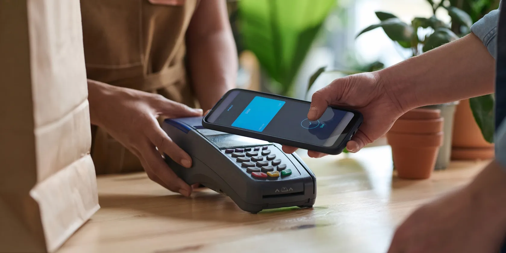 Ein Mann tätigt in einem Lebensmittelgeschäft eine NFC-Zahlung mit seinem Smartphone.