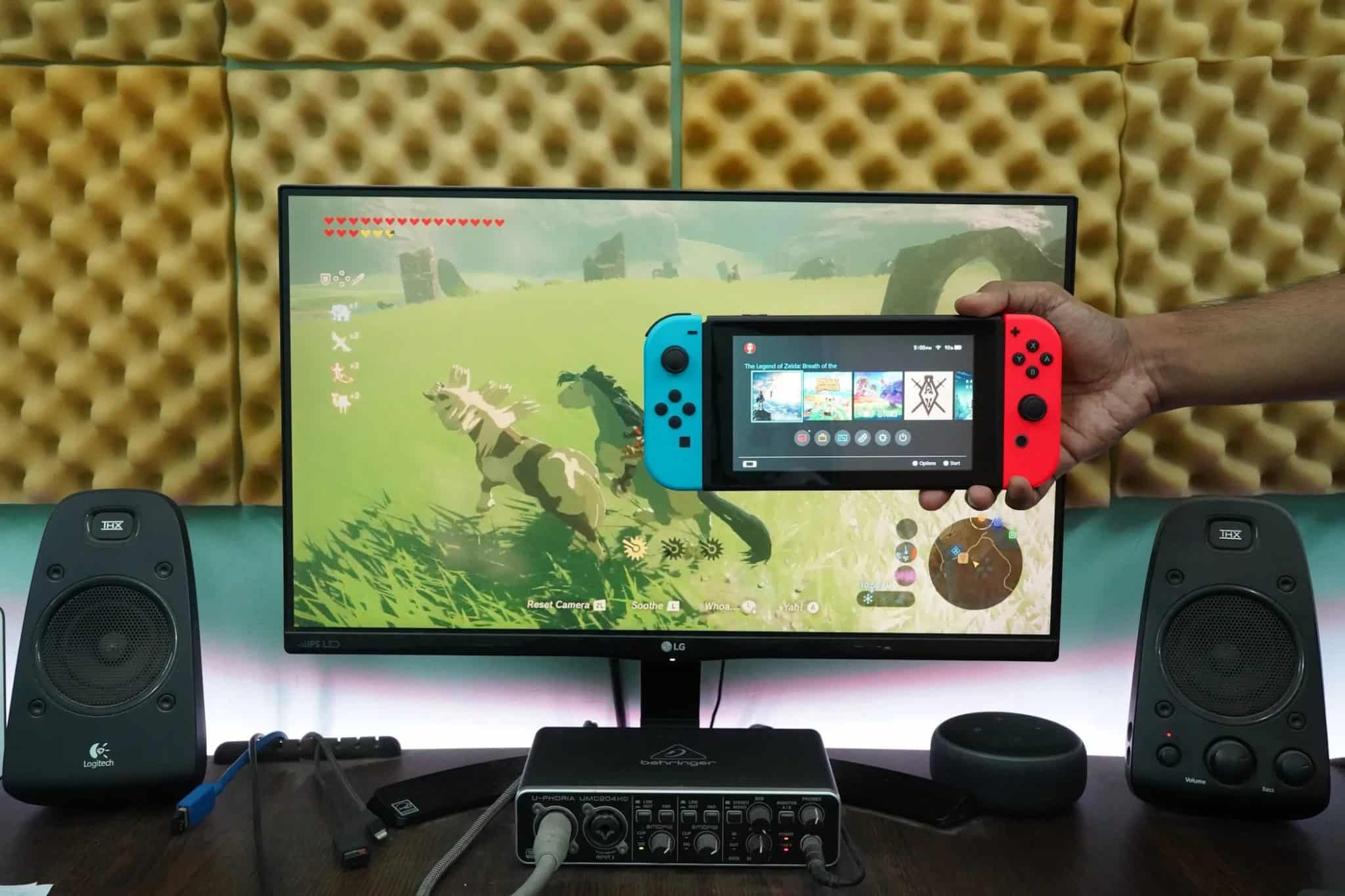 Άνδρας που κρατάει Nintendo Switch μπροστά στην οθόνη του υπολογιστή