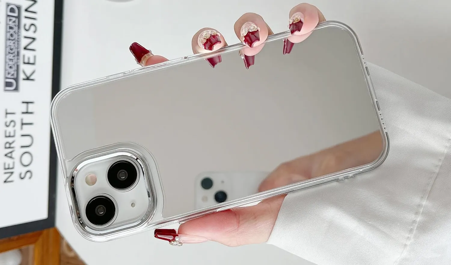 Eine Hand hält ein iPhone mit einer reflektierenden Spiegelhülle.