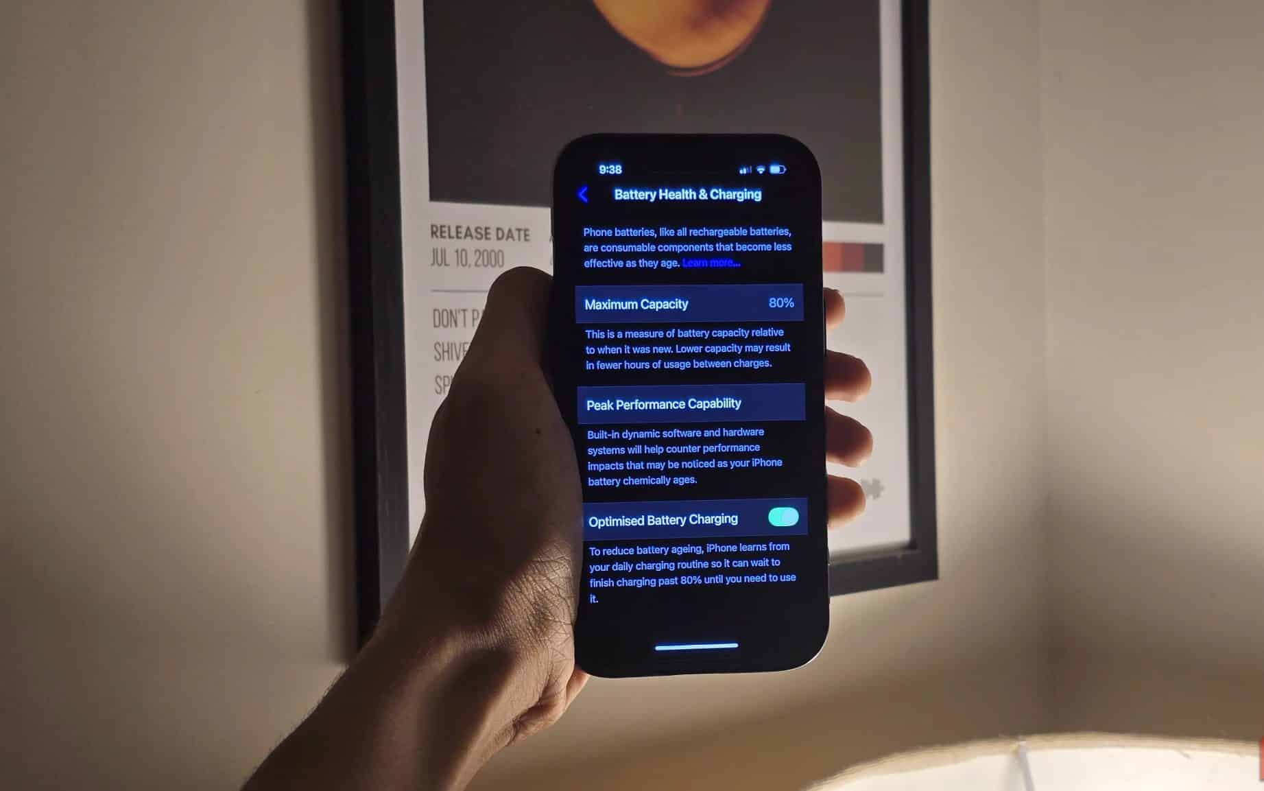 一個人拿著 iPhone，電池健康和充電菜單打開