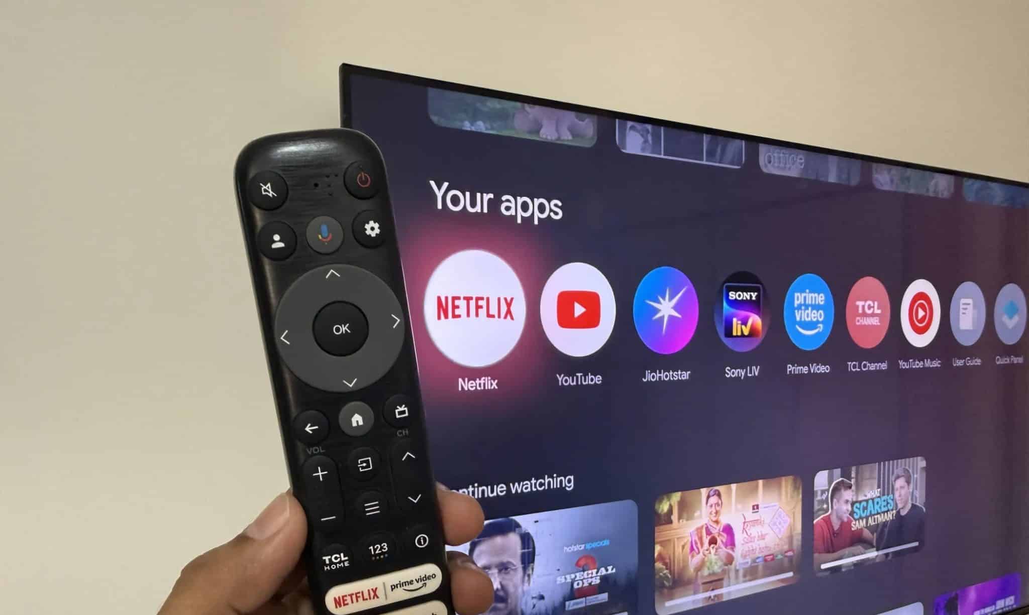 Mano che tiene il telecomando con Google TV sullo sfondo