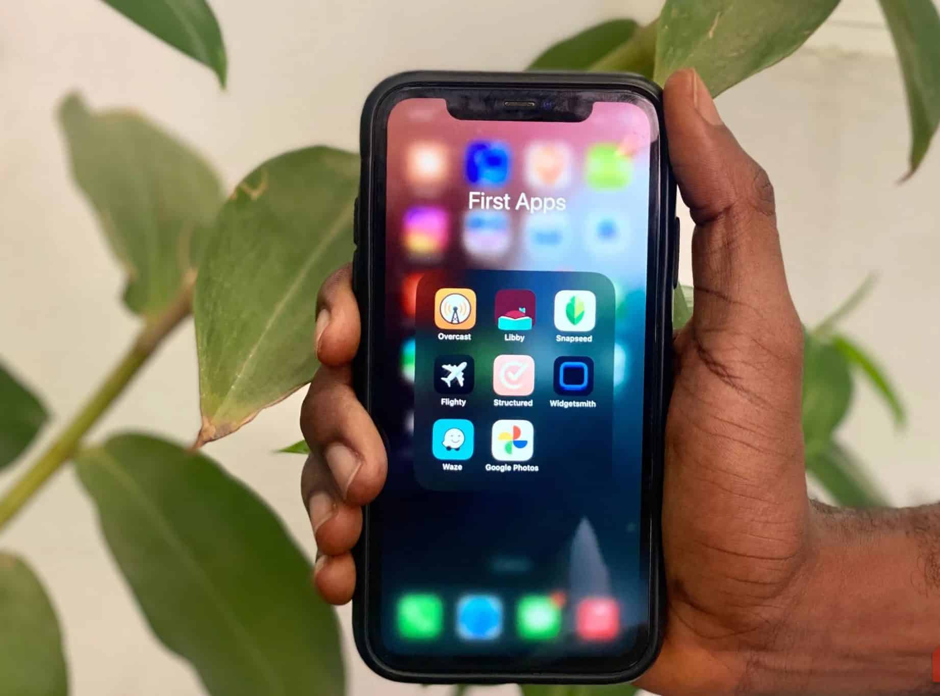 Una mano che tiene un iPhone che mostra una raccolta di app