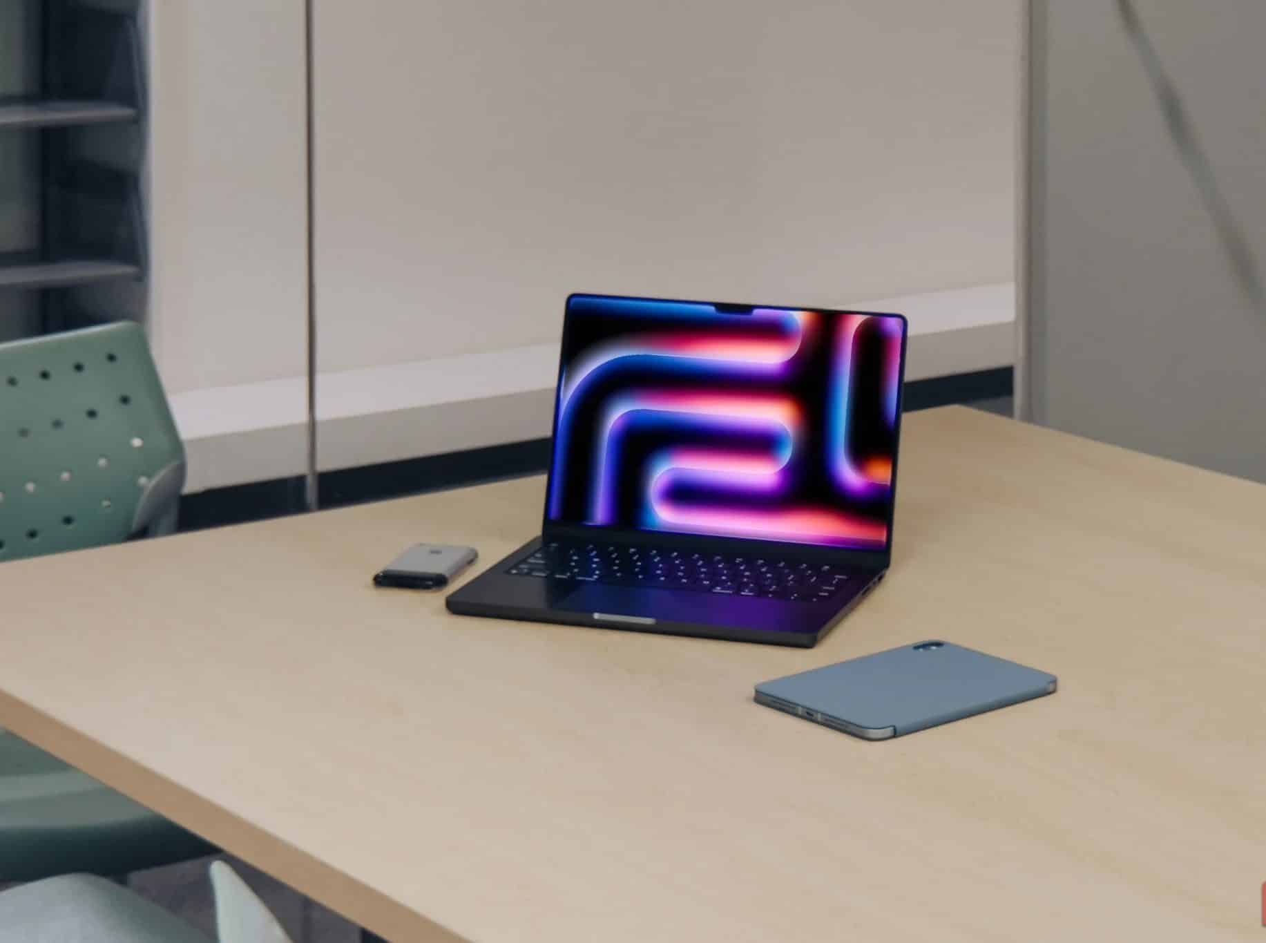 MacBook Pro M4 accanto a iPad e iPhone 2G su un tavolo di legno