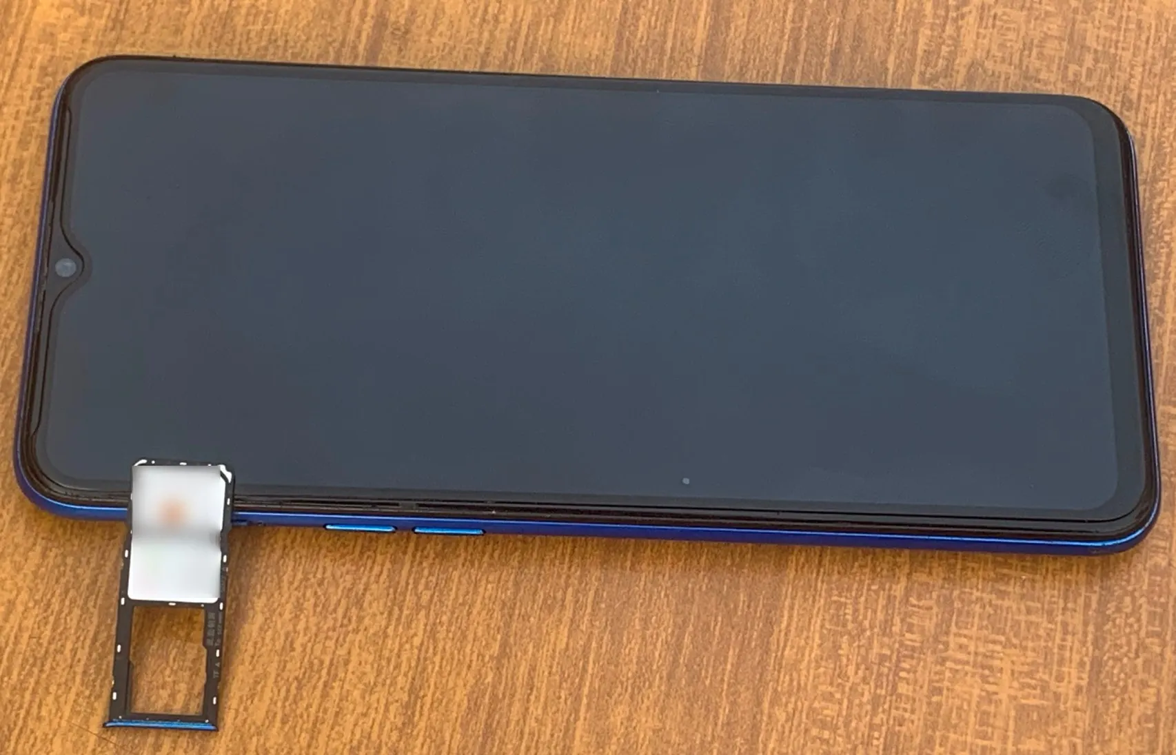 一台 Android 手機放在桌上,SIM 卡和記憶卡插槽都已移除。