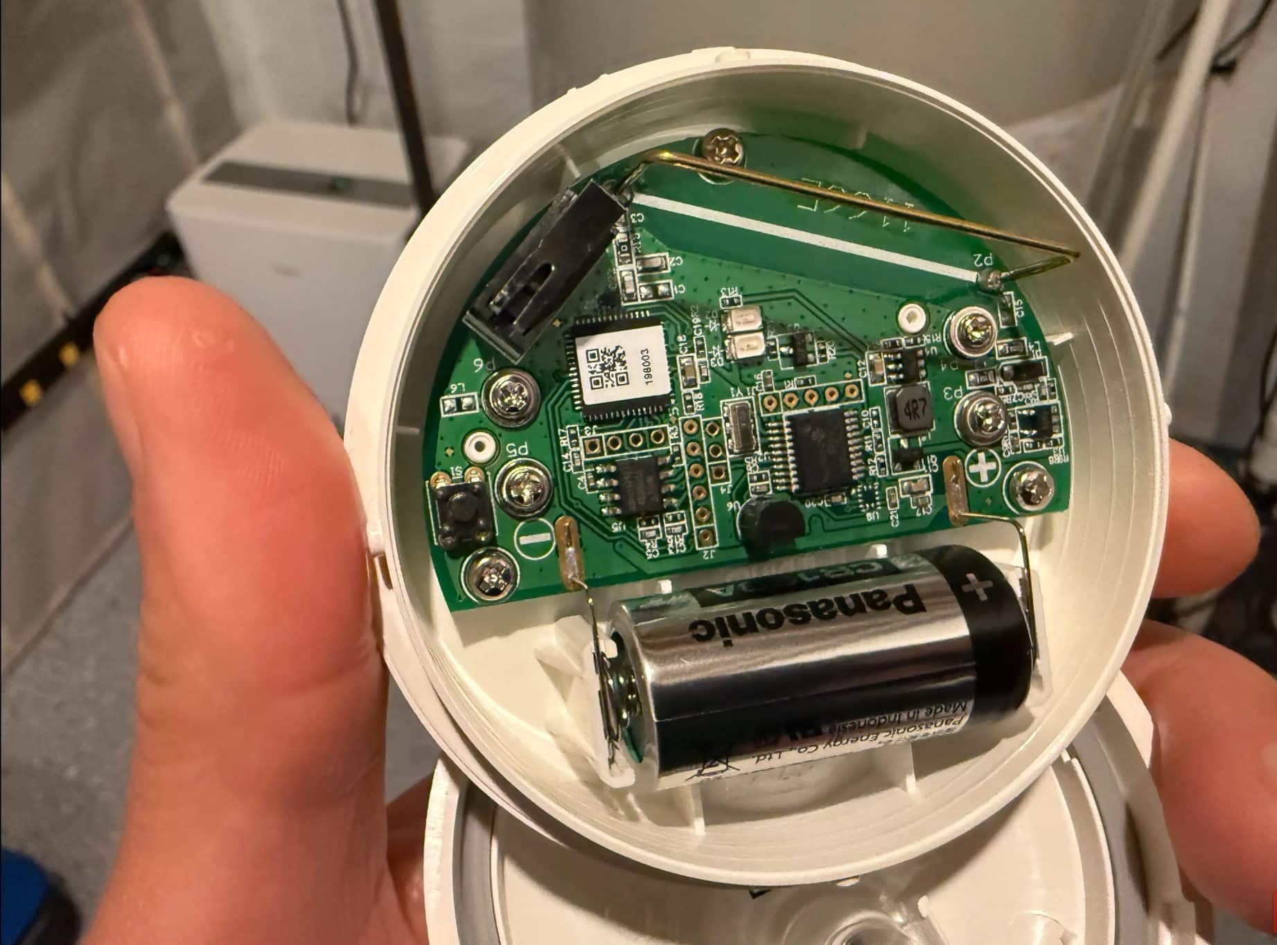 Una mano che tiene il sensore di allagamento e congelamento ad anello mostra la scheda elettronica.