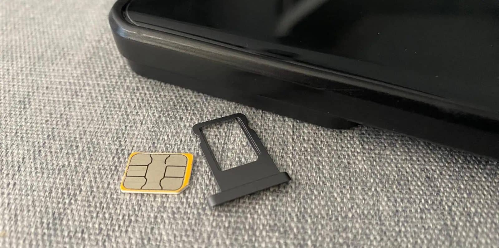 Scheda SIM e supporto di plastica accanto a un telefono cellulare su un tavolo