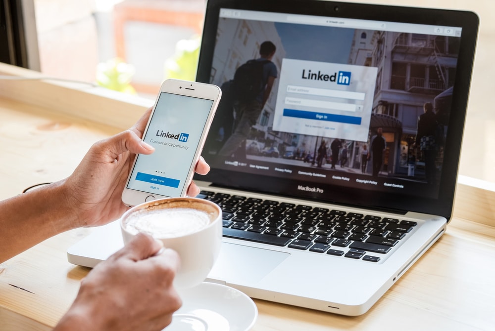 Ένα άτομο συνδέεται στο LinkedIn από το τηλέφωνο και τον φορητό υπολογιστή του.