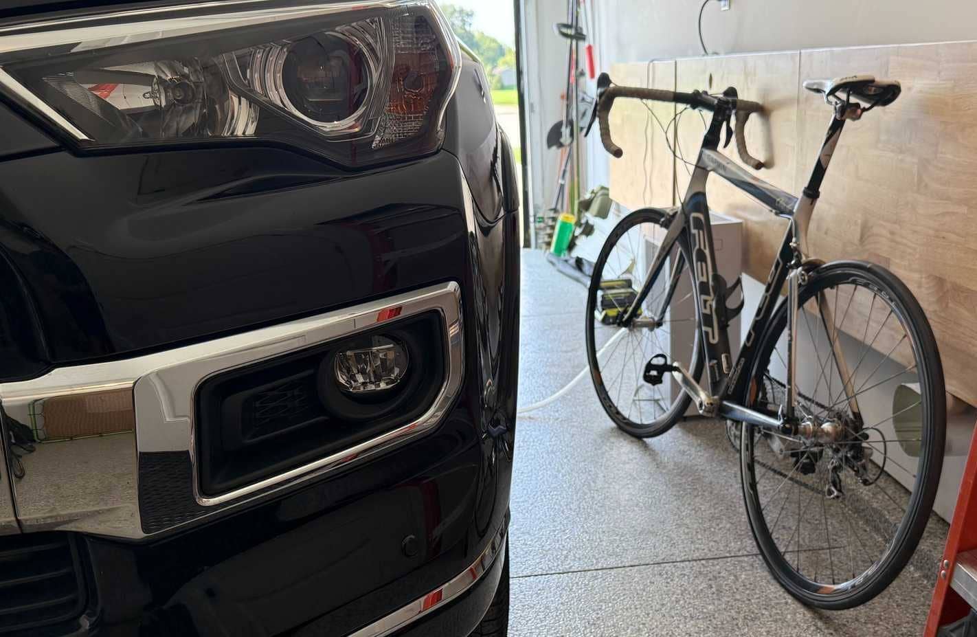 Bicicleta junto a un coche negro en el garaje