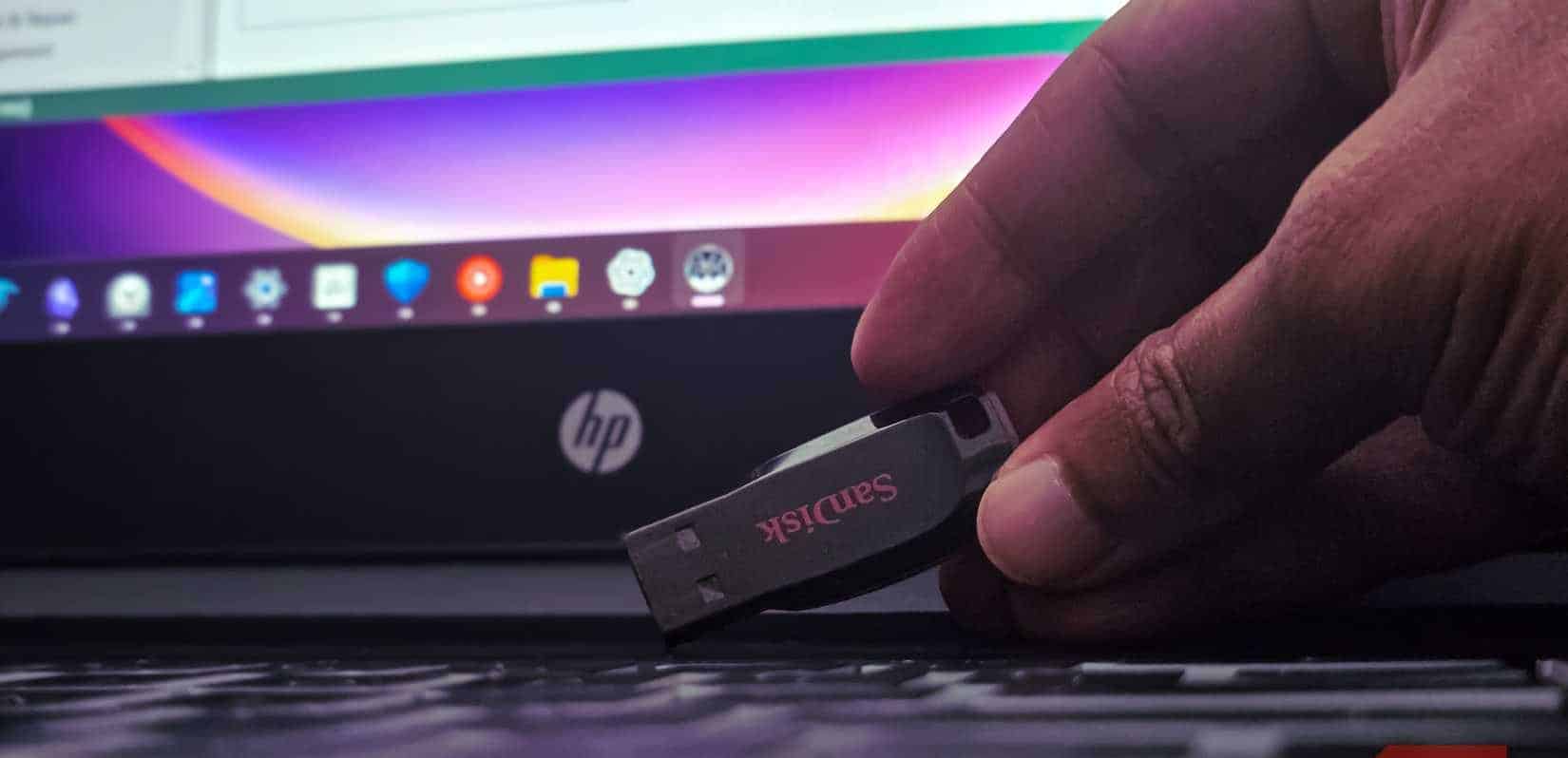 노트북 키보드 위에 샌디스크 USB 드라이브를 얹은 사람 손