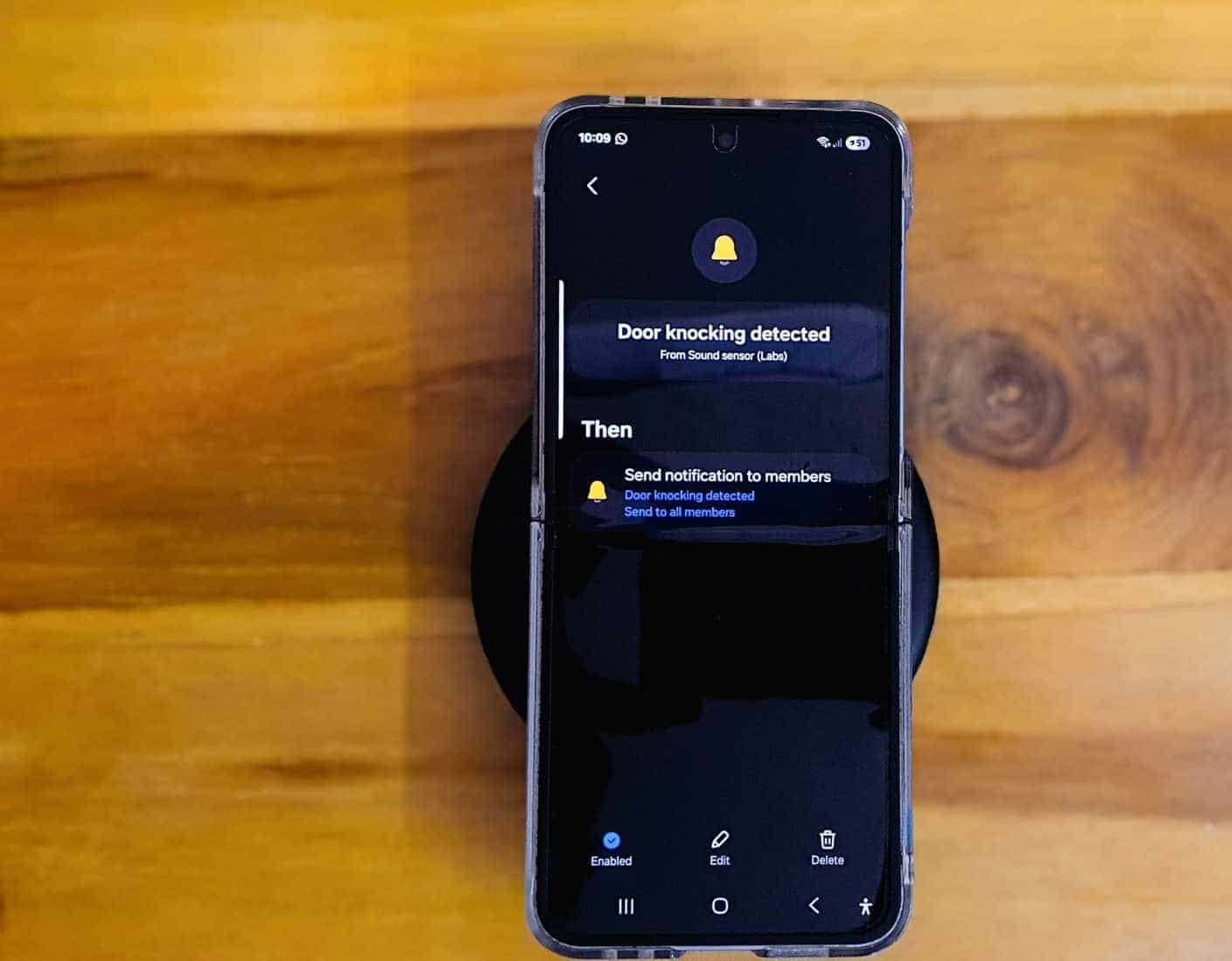 Telefon Samsung Galaxy Z Flip 6 położony na drewnianym stole z klawiaturą na krawędzi.