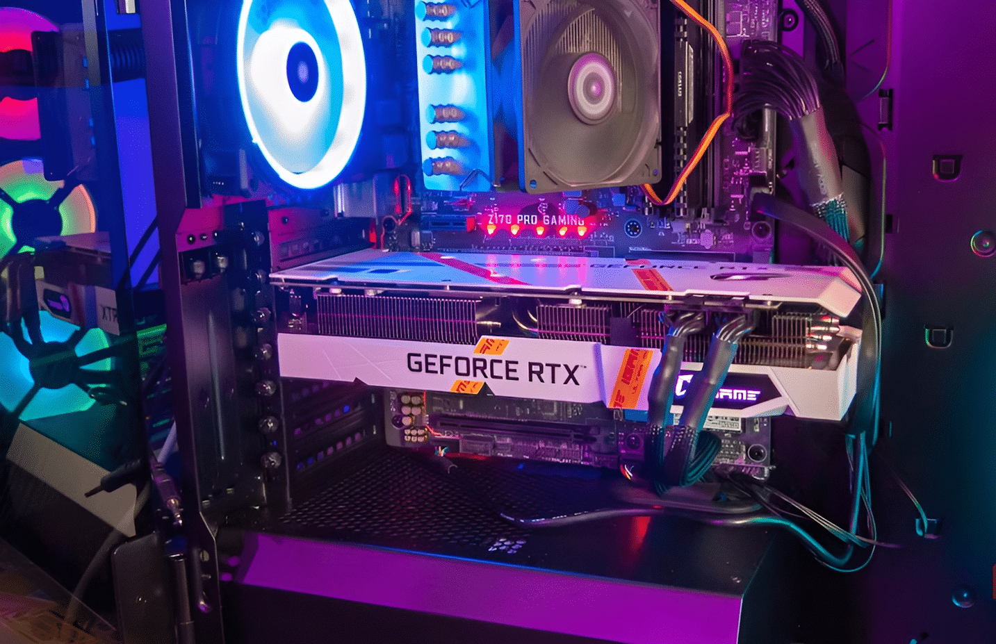Μια λευκή κάρτα γραφικών iGame GeForce RTX τοποθετημένη μέσα σε ένα περίβλημα gaming PC με φωτισμό RGB.