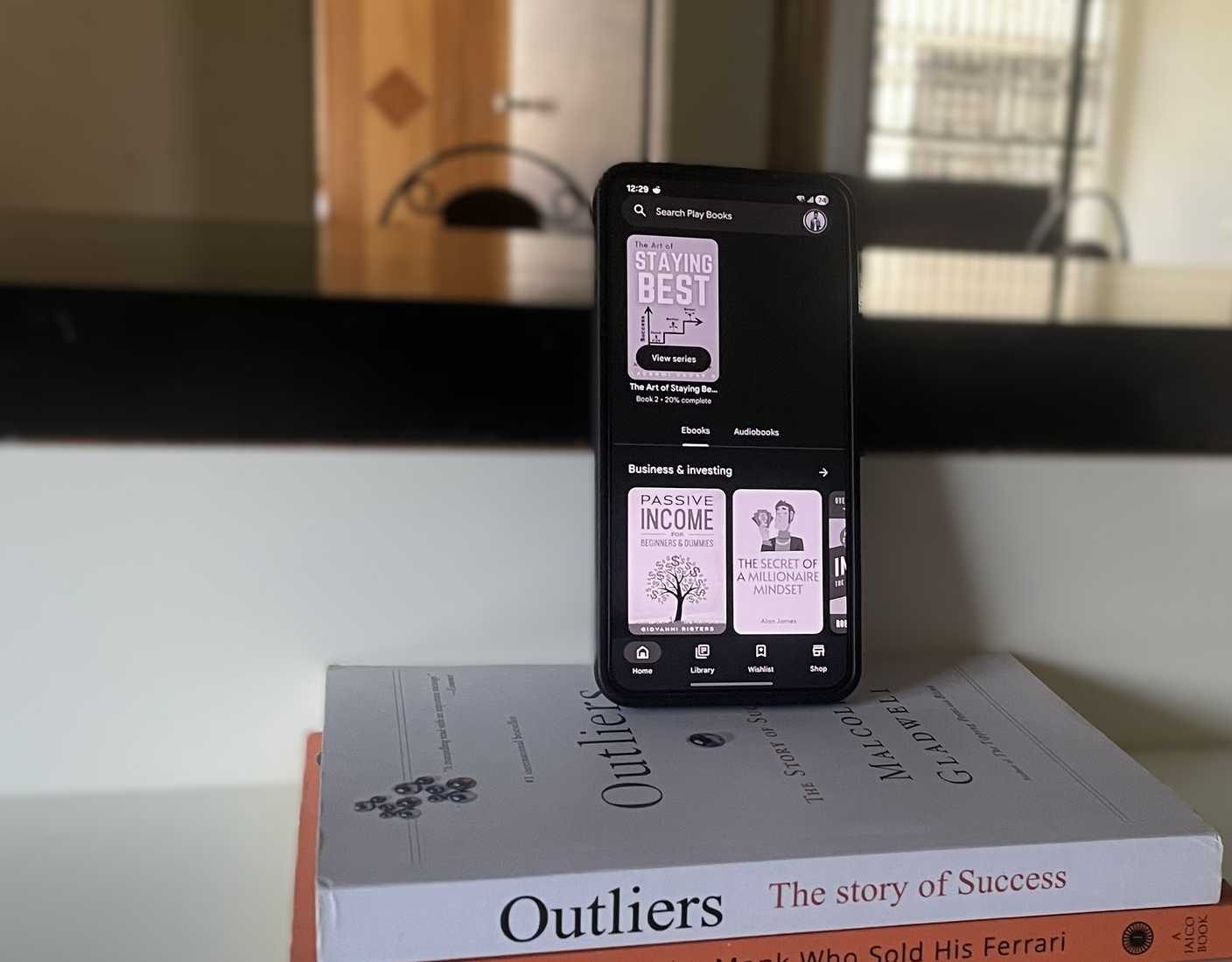 هاتف Android على كومة من الكتب يعرض كتابًا إلكترونيًا