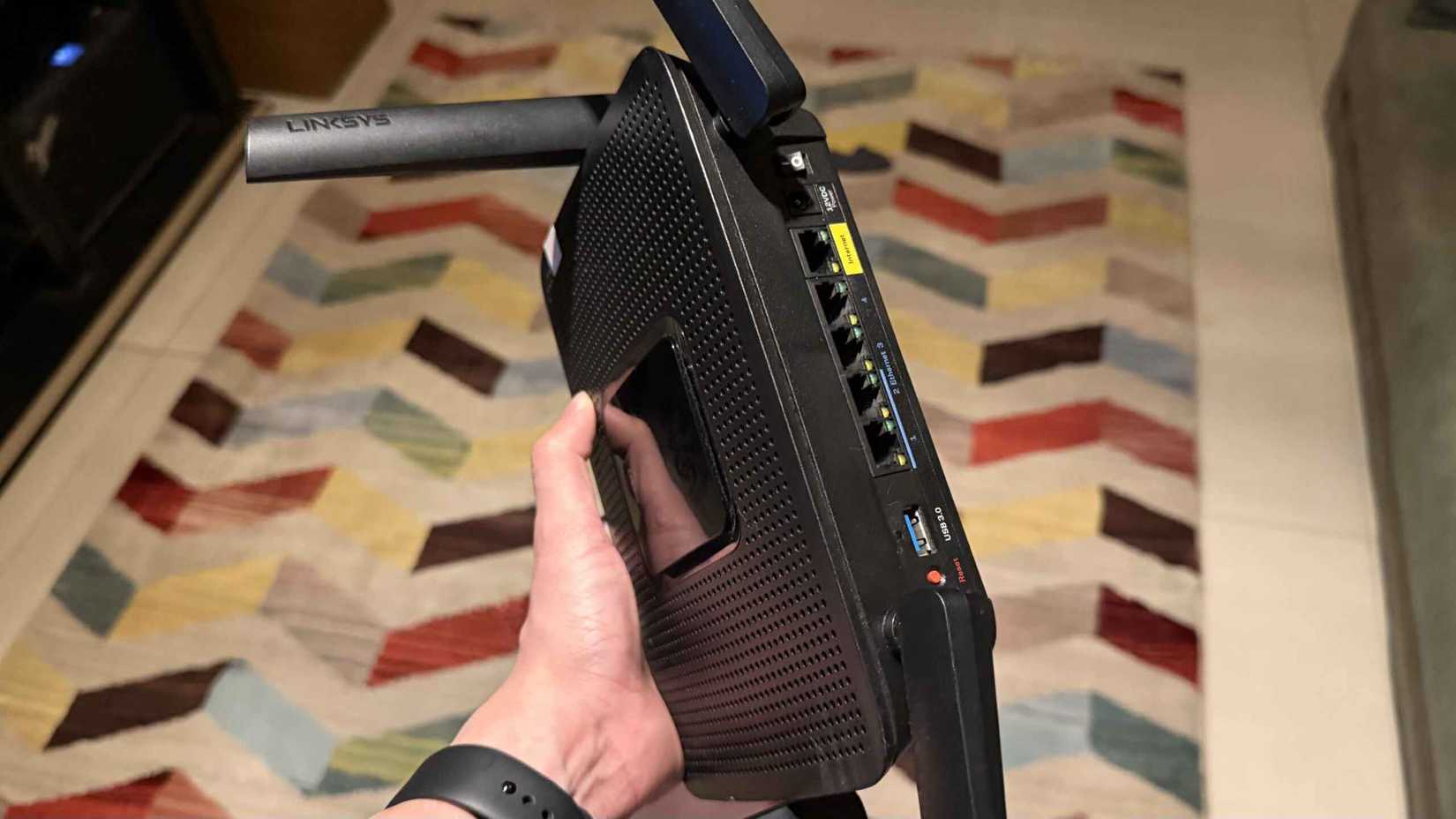 Dłoń trzymająca router Linksys EA8300 pokazuje porty z tyłu.