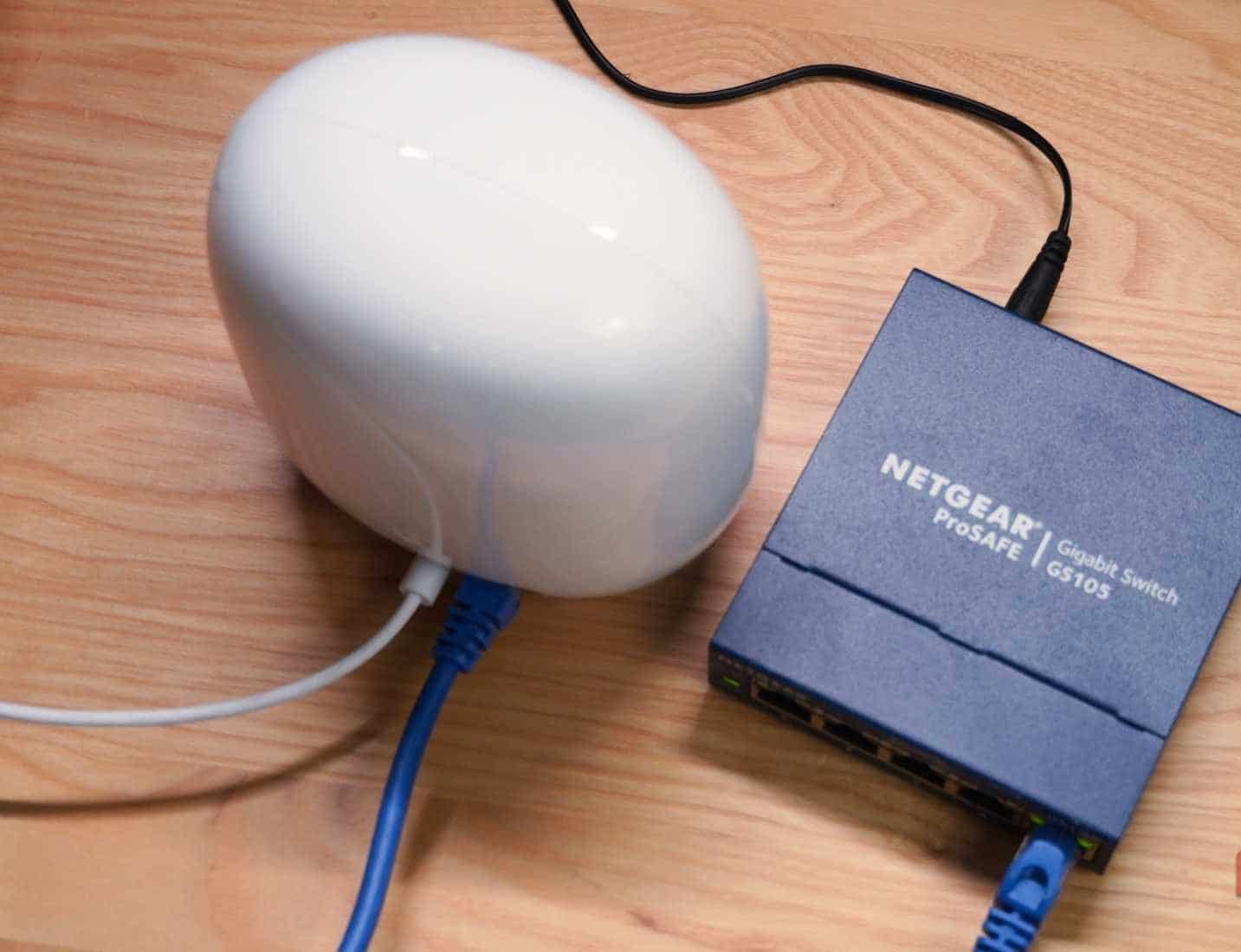 منظر من الأعلى لـ Google Nest Wi-Fi Pro متصل بمحول شبكات غير مُدار.
