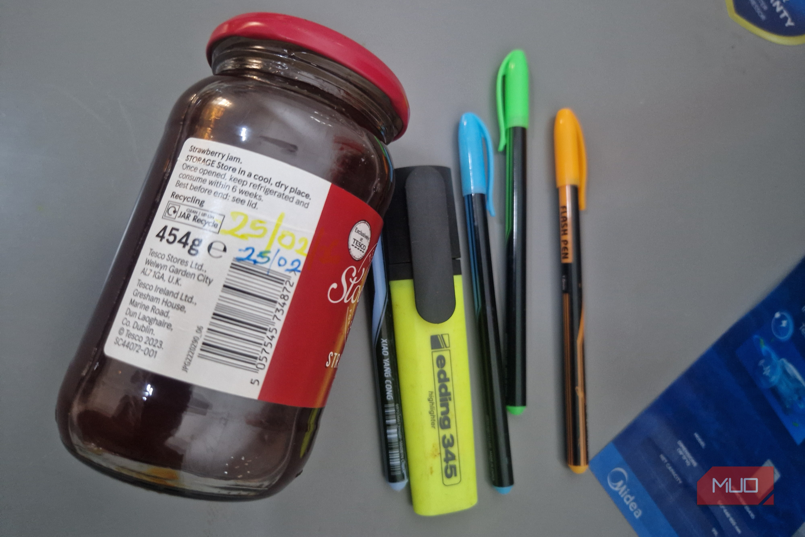 Matite Sharpie accanto a un barattolo di marmellata di fragole sul frigorifero.