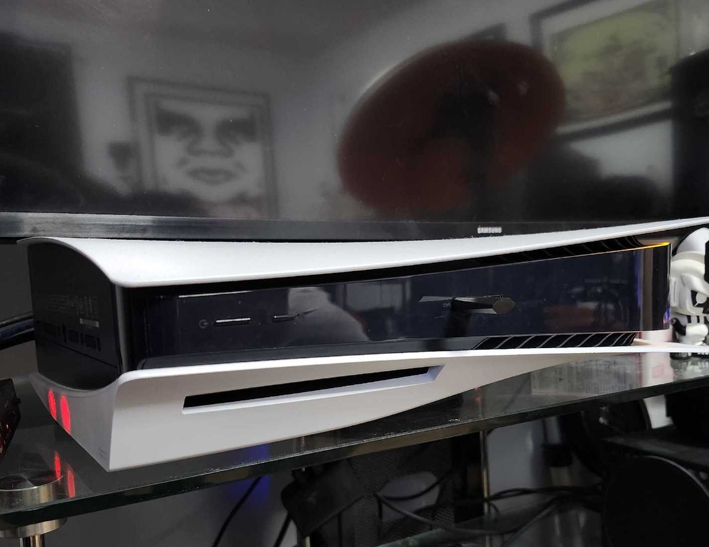 Bir PlayStation 5, cam bir masa üzerindeki akıllı televizyonun altına yerleştirilmiş.