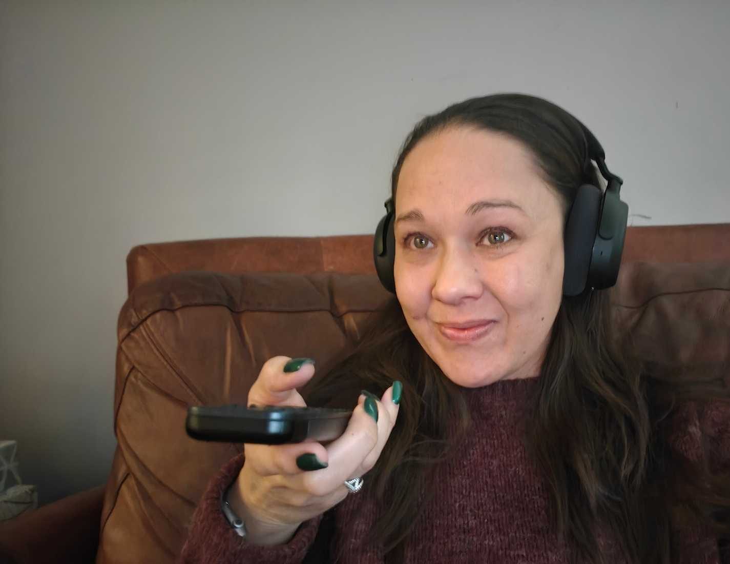 Una donna tiene in mano un telecomando e indossa delle cuffie Sennheiser RS 275.